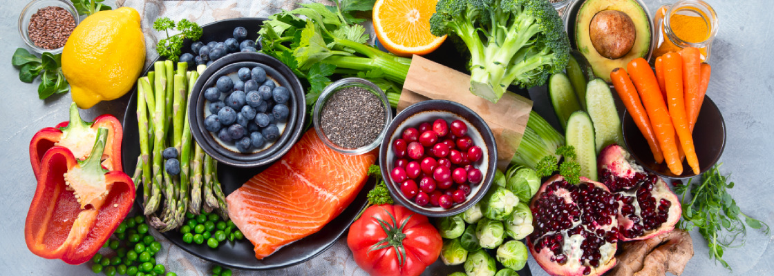 A top-down view of a variety of healthy vegetables, fruits and fish on a table