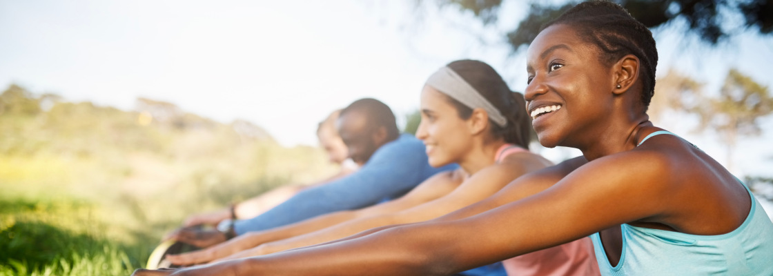 A group of people are seen stretching their legs in a sunny park, illustrating the importance of physical activity and the joy of spending time outdoors in nature