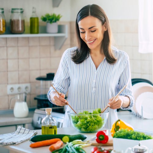 Woman cutting vegetables on a kitchen countertop, preparing healthy food in a kitchen
