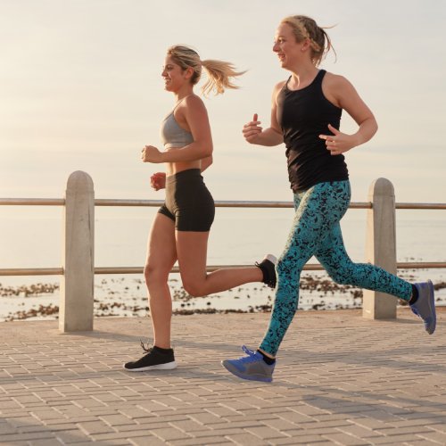 Two women are seen jogging along a beachside walkway, illustrating the importance of physical activity and the joy of exercising outdoors