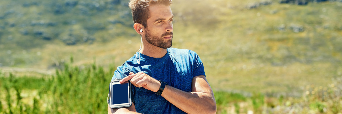Young man standing and resting while listening to music with earphones while exercise jogging